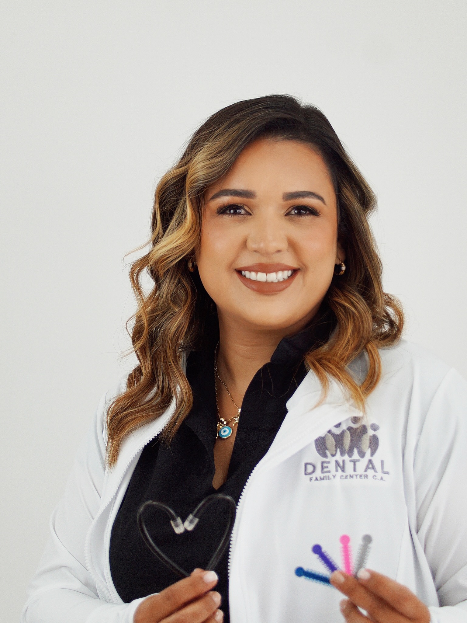 Odontóloga de Dental Family Center sonriendo con instrumental dental en su consultorio de Cagua